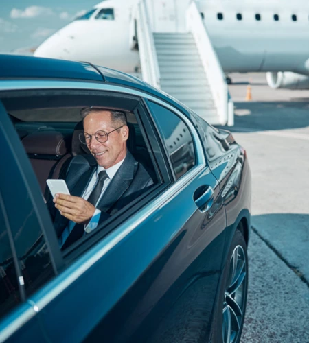 A business man sitting in a black limo at airport