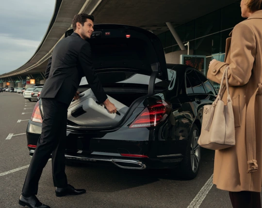 chauffeur loading the client's luggage in the car